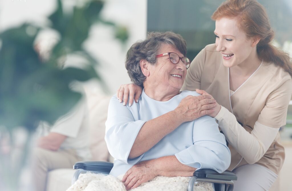 A female nurse smiling and talking to a female senior citizen patient in a wheelchair