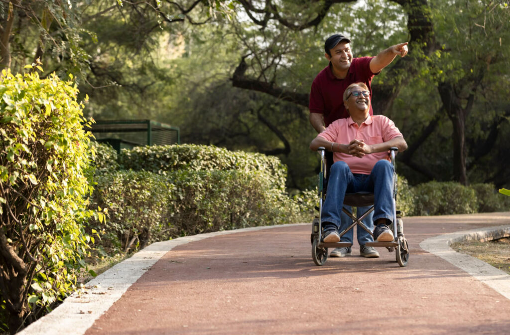 a man pushes his senior father in a wheel chair at a memory care community