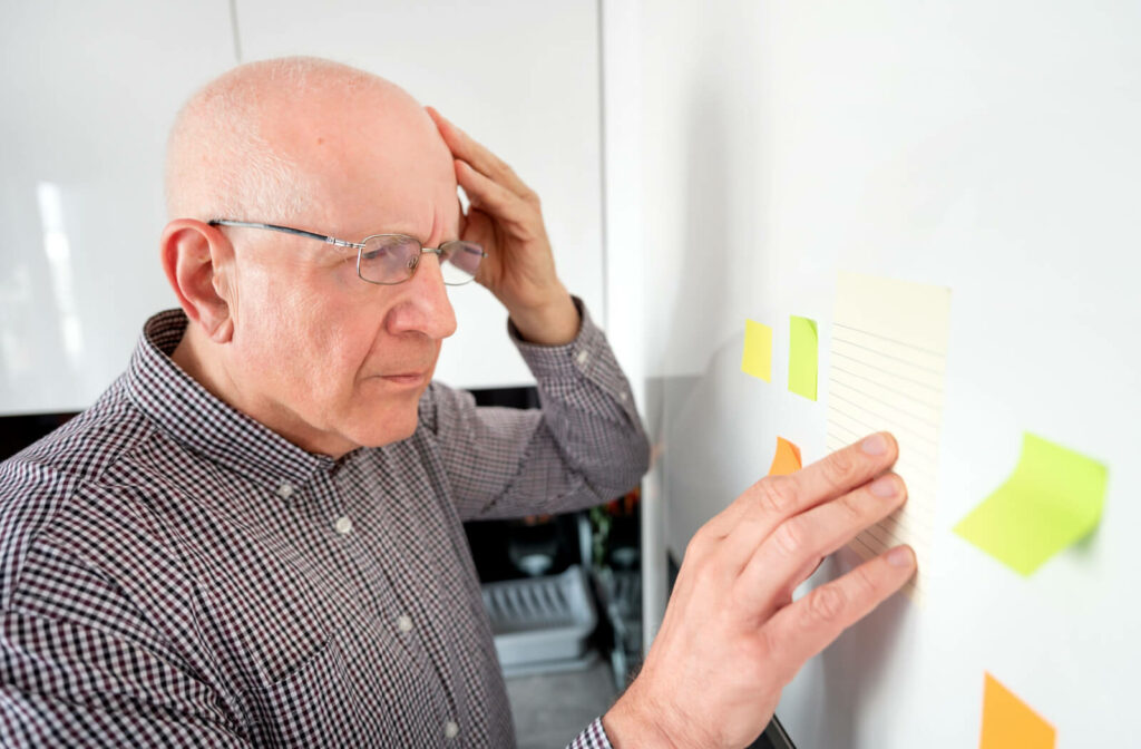 A senior person looking confused as he looks at a note taped on a wall.